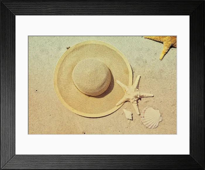 Framed Print : Seashells, Starfish, and hat arranged on beach