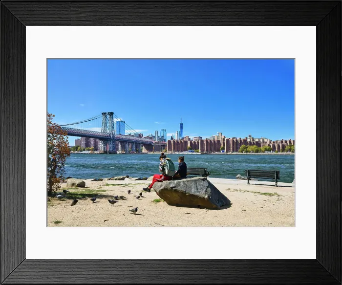 Framed Print : New York, New York City, Williamsburg Bridge with skyline from Grand Ferry Park, women on rock