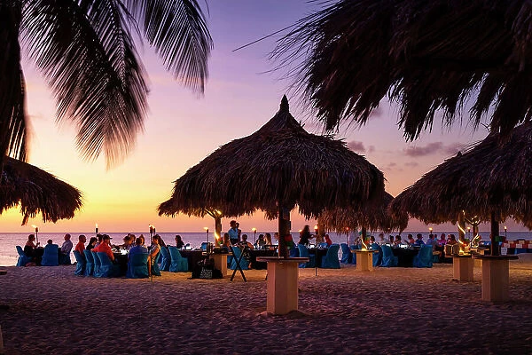 Aruba, Eagle beach scene at dusk with people dining by the sea