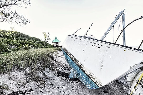 Boat wreck on beach with lifeguard tower in background