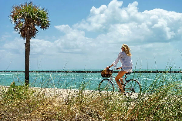 Florida, Miami Beach, South Pointe Park, Woman biking on the beach