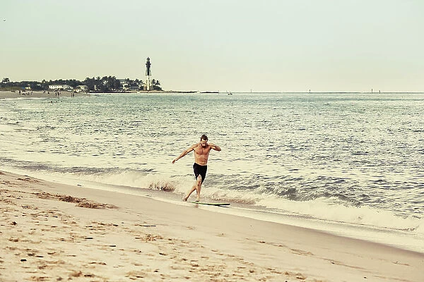Florida, South Florida, Surfer with Hillsboro Inlet Lighthouse in background
