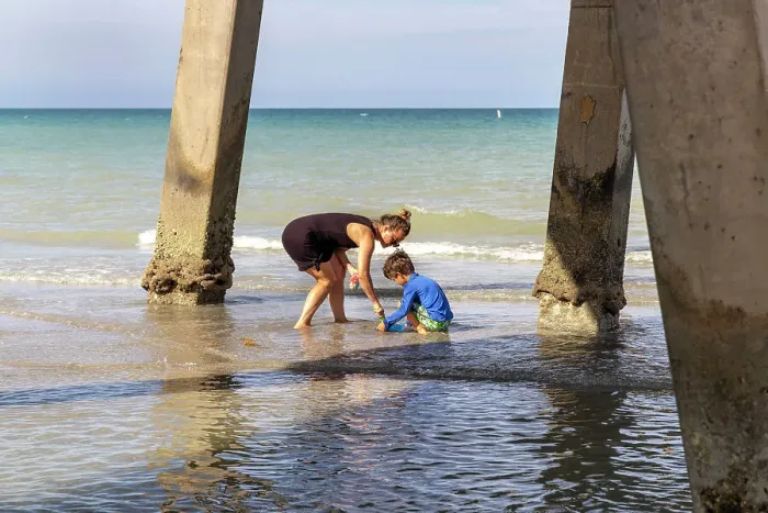 Framed Print : Mother and child playing at the beach, under a pier Framed Print : Mother and child playing at the beach, under a pier