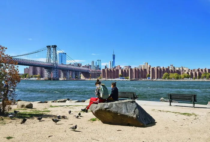 Framed Print : New York, New York City, Williamsburg Bridge with skyline from Grand Ferry Park, women on rock