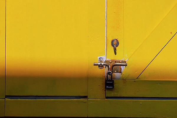 Pad lock on yellow wooden door