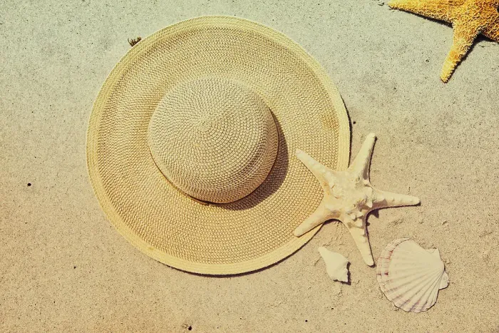 Framed Print : Seashells, Starfish, and hat arranged on beach
