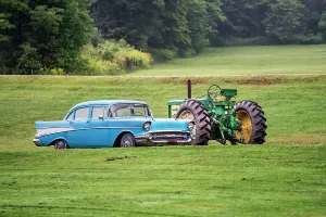 Americana scene, sky blue Chevrolet car next to a John Deer tractor