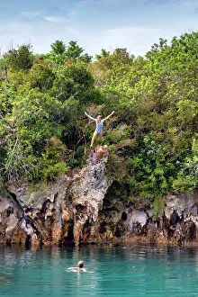 Bermuda, Blue Hole Park, Woman jumping into aquamarine swimming hole