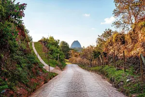 Colombia, Antioquia, Rural road with view of Penon de Guatape Rock