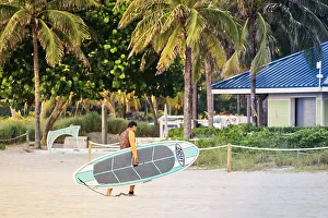Florida, South Florida, Pompano Beach, man walking with surfboard