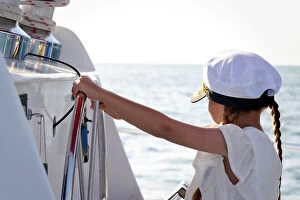 Images Dated 30th March 2023: Little girl at helm wearing captain hat