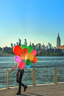 New York City, Brooklyn, Williamsburg, man with balloons walking along the promenade at Domino Park