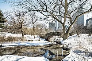 USA, New York City, Manhattan Central Park, Gapstow bridge in winter with snow, skyscrapers