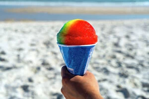 Images Dated 15th July 2022: USA, New York, Long Island, Jones Beach, hand holding a colorful snow cone with the beach
